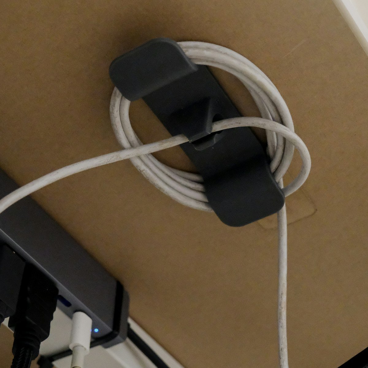 Cable clip holding a coiled cable under a desk